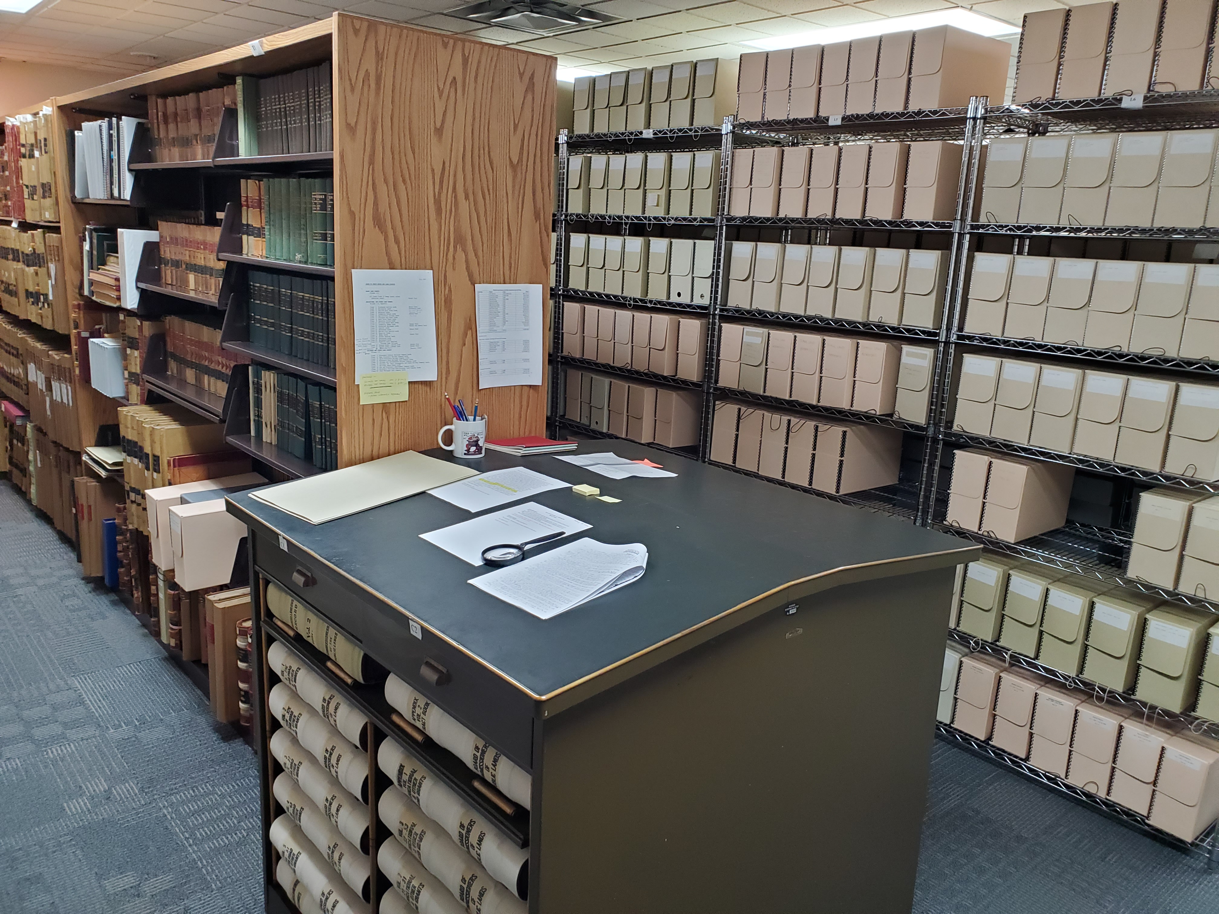 Inside the BCPL archive featuring historical volumes on shelves and a table being used to review historical documents