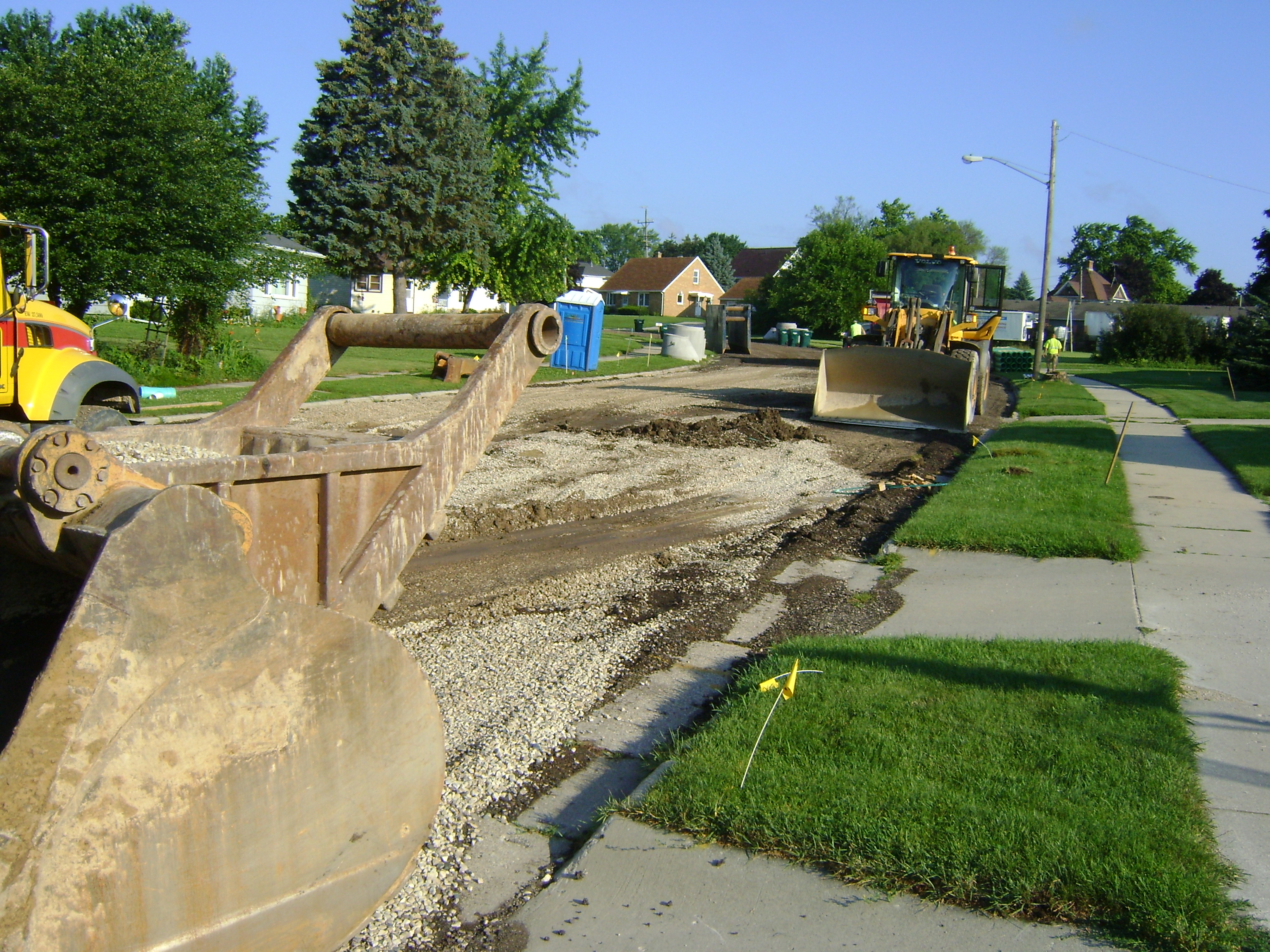 City of Kewaskum street with existing pavement removed with several large construction vehicles and equipment visible