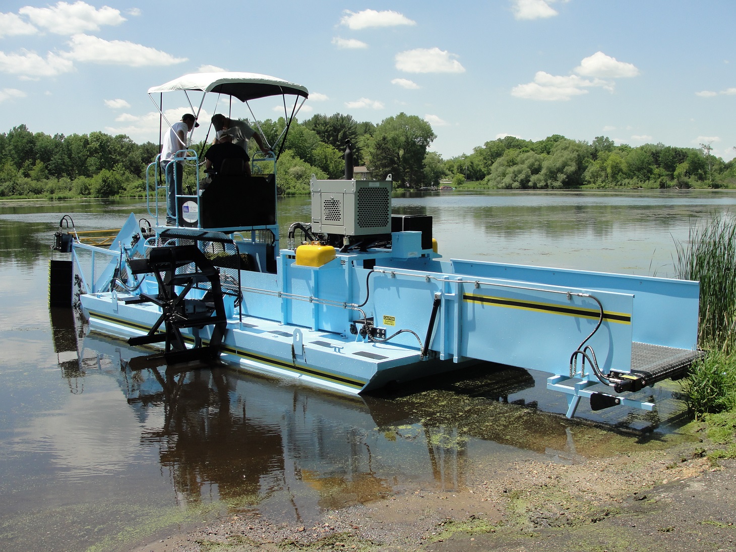 White River Lake District sky blue weed harvester on a trailer with the board members poised in front of it.